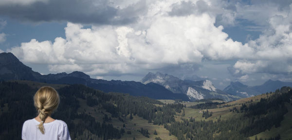 Rear view of woman looking at mountains against sky