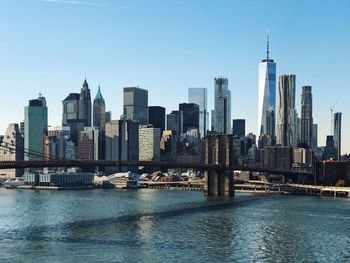 Brooklyn bridge and east river against sky in city