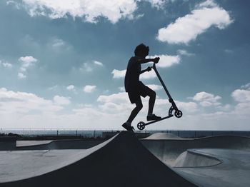 Full length of boy performing stunt with push scooter in city