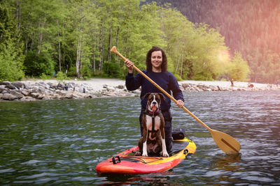 Man holding boat in lake against trees