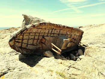 Abandoned boat on beach against sky