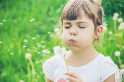 Close-up of young woman blowing flowers