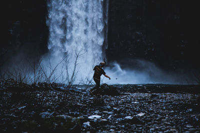 Man standing by waterfall in forest