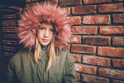 Portrait of teenage girl against brick wall