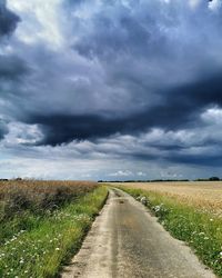 Road amidst field against sky