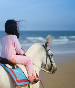 Rear view of girl riding horse in sea
