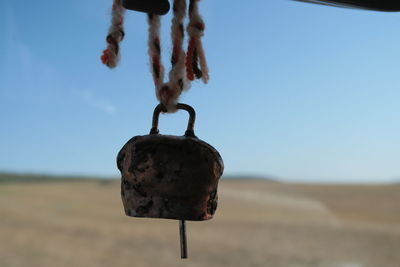 Close-up of metal hanging against sky