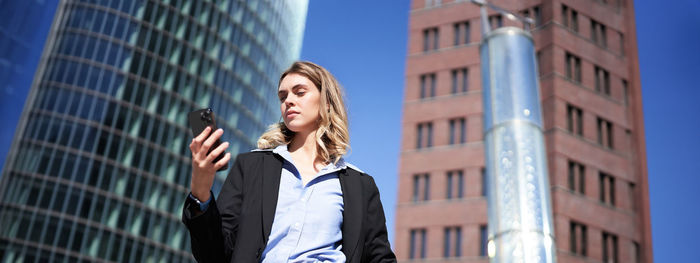 Portrait of businessman standing against building