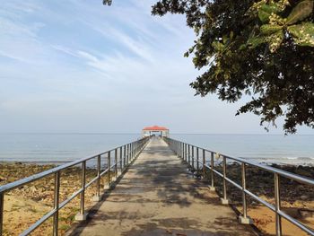 Walkway by sea against sky