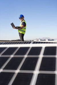 Technician working on laptop at solar panel station