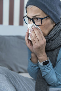 Feverish senior woman blowing her nose