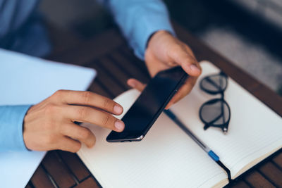 Midsection of man using mobile phone on table