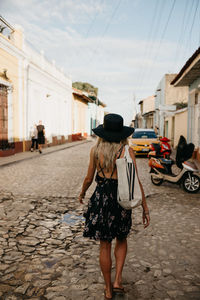 Rear view of woman walking on street against buildings in city