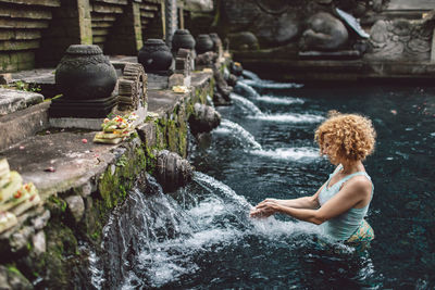 Rear view of woman in water at temple