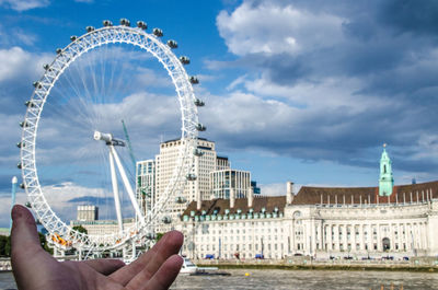 Ferris wheel in city against cloudy sky