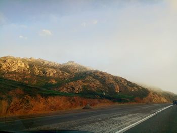 Road by mountains against sky
