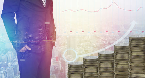 Digital composite image of businessman with coins standing against cityscape