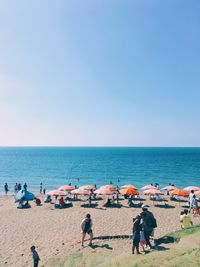 People on beach against clear sky