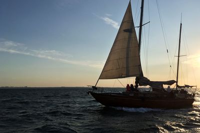 Sailboat sailing on sea against sky during sunset