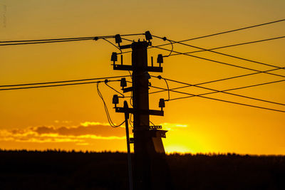 Low angle view of silhouette electricity pylon against sky during sunset