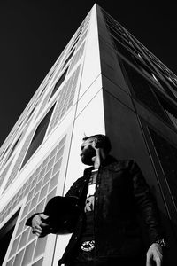 Mature man holding sports helmet while standing against building