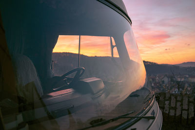 Tilt image of car on land against sky during sunset
