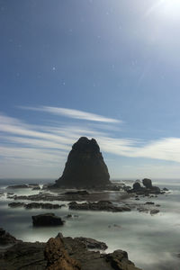 Rock formation on beach against sky