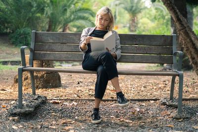 Full length of woman sitting on bench in park