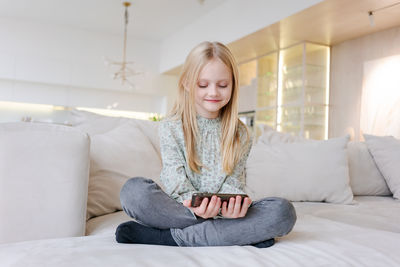 Young woman using laptop while sitting on bed at home