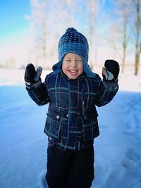 Boy wearing hat standing in snow during winter