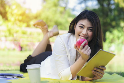 Portrait of young woman using phone while sitting outdoors