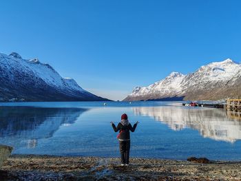 Rear view of woman walking on lake against clear blue sky