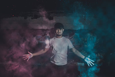 Digital composite image of man standing amidst powder paint at night