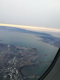 Aerial view of city by sea against sky during sunset