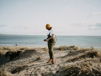 Full length of woman standing at beach against sky