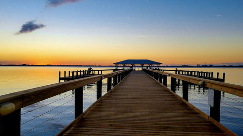 Pier over sea against sky during sunset