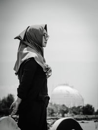 Side view of woman standing against sky