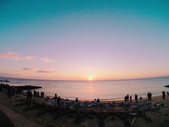 Silhouette people on beach against sky during sunset