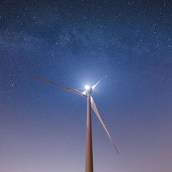 Low angle view of wind turbines against star field