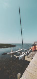 Sailboats moored in sea against clear sky
