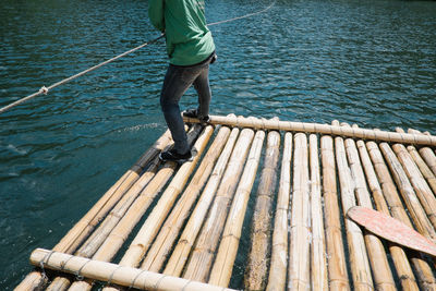 Low section of man standing on wooden pier over lake