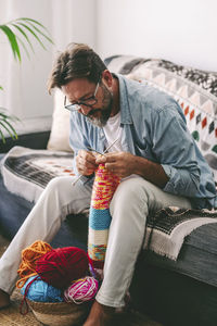 Side view of man sitting on sofa at home