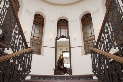 Low angle view of young woman sitting against mirror