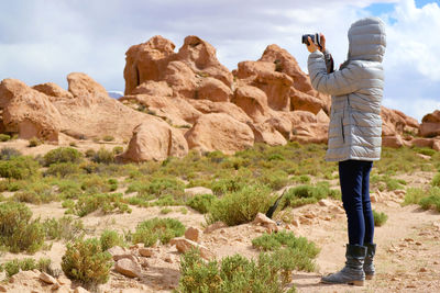 Female shooting photos of landscape with plenty of rock formations in siloli desert, bolivia