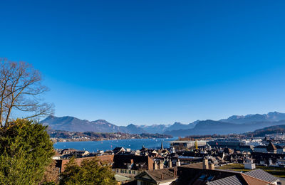 High angle view of townscape by sea against clear blue sky