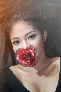 Portrait of young woman carrying red rose in mouth