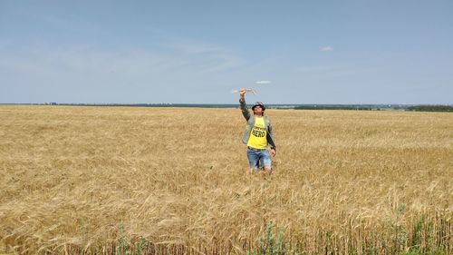 Boy standing on field against sky