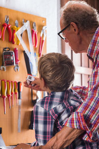 Rear view of man explaining tools to boy in workshop