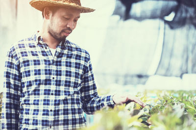 Male farmer touching crops growing in greenhouse