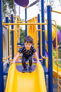 Full length of cute girl sliding in playground